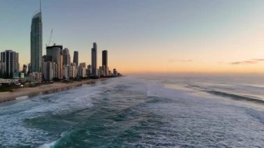 Güneş doğarken Altın Sahil 'in havadan görünüşü. Dalgalar yavaşça sahile vuruyor. Şehrin ufuk çizgisini aydınlatıyor.