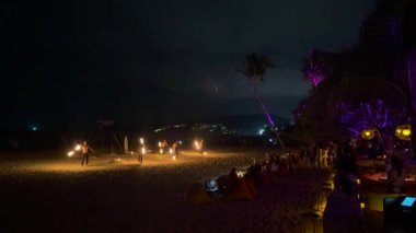 Ateş dansçıları gece Karon Sahili, Phuket 'te gösteri yapıyorlar. Canlı alevler sahneyi aydınlatır, büyüleyici ve enerjik bir atmosfer yaratır.