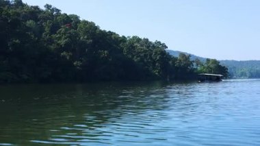 Orman tepelerinin yakınındaki sakin sularda bir tekne hareket ediyor..