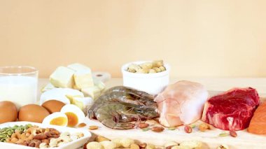 Etler, deniz ürünleri, fındıklar ve süt ürünleri de dahil olmak üzere çeşitli protein zengini gıdalar parlak ışık altında bir masanın üzerine güzelce yerleştirilmiştir.