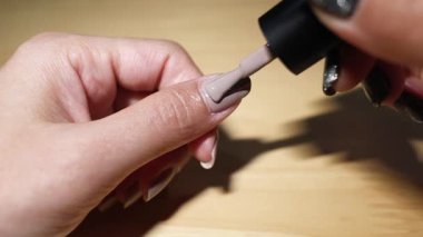 Tırnaklarına aşamalı olarak oje sürüyorum.