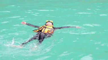 Temiz suda can yeleğiyle şnorkelle yüzen biri.