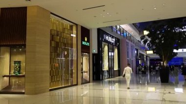 Lüks bir alışveriş merkezinde yürüyen biri.