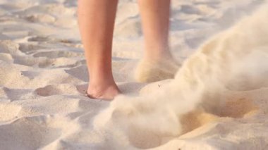 Karon Sahili, Phuket, Tayland 'da çıplak ayakla kum tekmeleyen kişi.