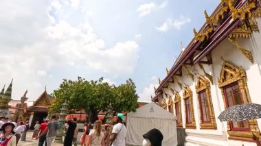 Turistler, Bangkok 'taki Wat Phra Kaew Tapınağı' nı gezerek, aydınlık gün ışığında onun dekoratif mimarisini yakalıyorlar.