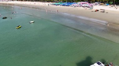 Drone görüntüleri Phuket, Tayland 'daki canlı sahil yaşamını, güneşli gökyüzünün altında tekne, yüzücü ve renkli şemsiyeleri yakalıyor.