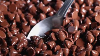 Kaşık yığından çikolata parçaları topluyor.