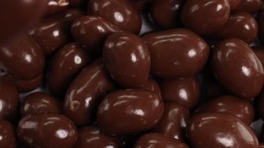 Çikolata kaplı fındıklar güzelce taşarak zengin ve dokulu bir desen oluşturuyor. Ilık aydınlatma parıltılı yüzeyi güçlendirir, hareket ve hoşgörüyü vurgular