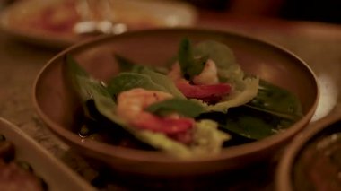 Tahta bir tabakta karides miang kham yakın plan, sıcak, çevresel aydınlatma altında, taze malzemeler ve canlı renkler vurgulanıyor