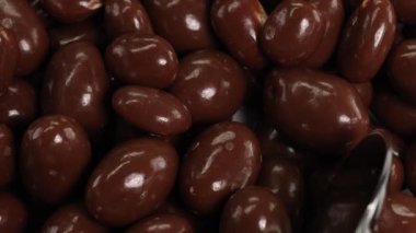 Bir kaşık parlak çikolata kaplı fıstıkları kepçeler, yumuşak ışık altında parlak desen ve parlaklığı yakın çekim görüntüsüyle