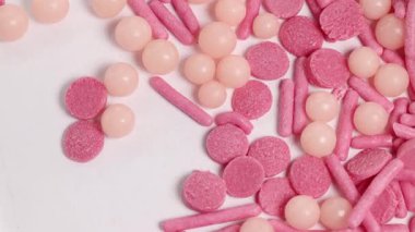 Parlak ışık altında dönen, çeşitli şekil ve dokuları gösteren pembe şekerlerin yakın çekim videosu