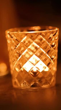 Bir mum nazikçe kristal bir camın içinde titreşir, sıcak, ortam ışığını sıcacık bir ortamda bırakır.