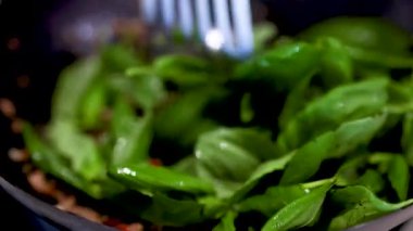 Canlı yeşillikler ve zengin dokularla dolu bir mutfak ortamında biftek ve fesleğen kızartma hazırlığı.