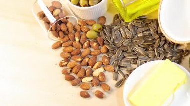 Hafif ahşap bir yüzeye yerleştirilmiş fındık, tohum, yağ ve avokado gibi sağlıklı yağlar.