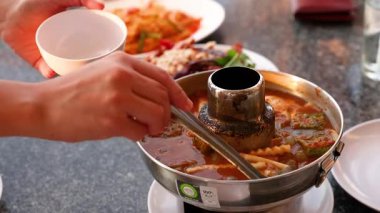 Eller sıcak tencereden kaseye çorba servis ediyor.