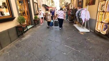 İnsanlar işlek bir alışveriş caddesinde yürüyor