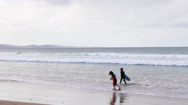 Okyanusta yürüyen iki sörfçü