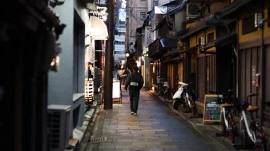 Tuhaf, dar bir sokakta yürüyen biri.