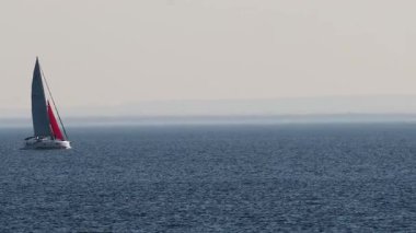 Sakin okyanus sularında süzülen yelkenli.
