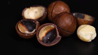 Macadamia fındıkları koyu bir arka planda düzenlenmiş.