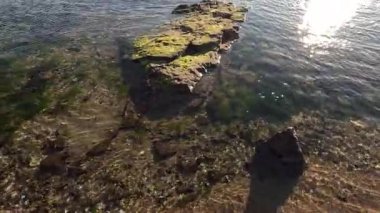 Gün doğumu kayaları aydınlatıyor ve okyanus sularını sakinleştiriyor.