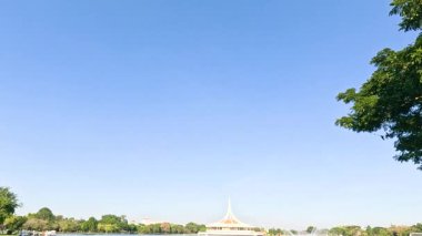 Ziyaretçiler, Bangkok 'taki Suan Luang Rama IX Parkı' ndaki açık mavi gökyüzünün altında sakin bir öğleden sonranın tadını çıkarıyorlar.