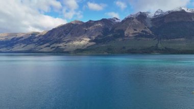 Glenorchy, Yeni Zelanda 'da dağlı sakin bir göl manzarası. Açık gökyüzü ve sakin sular huzurlu bir atmosfer yaratır.