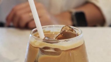 Buzlu kahveyi pipetle karıştırıyorum.