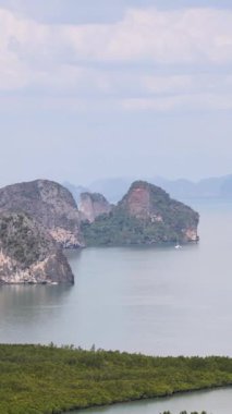 Tayland, Phang Nga 'daki yemyeşil adaları ve sakin suları görüntüler. Parlak gün ışığı doğal güzelliği ve dingin atmosferi arttırır.