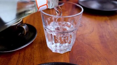 Masadaki bardağa su dökülüyor.