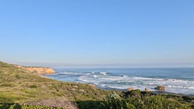 Gün batımında dalgalar kayalara çarpıyor.