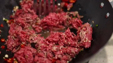 Yer eti tavada baharatlarla kızartılır, canlı renkler ve dinamik pişirme hareketi vurgulanır.