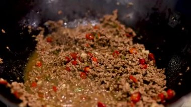 Etli, fesleğenli ve biberli canlı bir kızartma. Parlak ışıklandırma taze malzemeler ve dinamik yemek pişirme eylemini vurguluyor