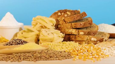 Parlak mavi arkaplanı olan bir masada çeşitli tahıl ve ekmekler sergileniyor. Dokular ve renkler vurgulanıyor.