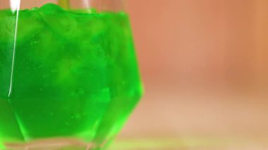 Yeşil sıvı bardağa dökülüyor.