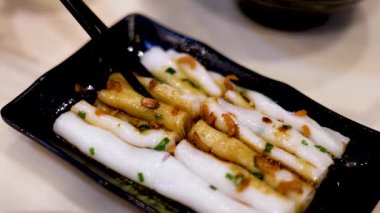 Çubuklar siyah tabaktan erişte kaldırıyor.