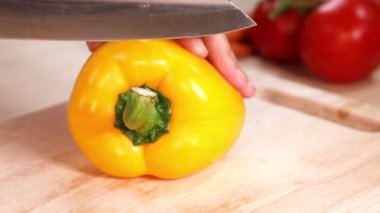 Gemide sarı bir dolma biber kesen eller.