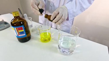 Bir bilim adamı iyot saat reaksiyonu gerçekleştiriyor. Laboratuvar ortamında kimyasalları hassas ölçümler ve kontrollü ışıklandırma ile karıştırıyor.