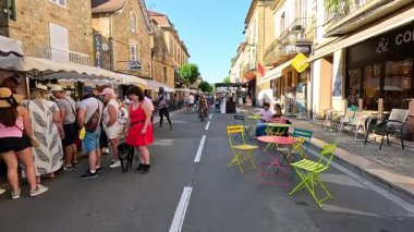İnsanlar hareketli bir sokak pazarında alışveriş yapıp yemek yiyorlar.