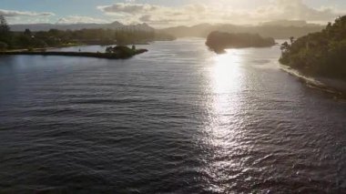 İnsansız hava aracı Brunswick Heads nehrinin üzerinde sakin bir gün batımını yakalıyor, yansıtıcı suyu ve bereketli çevreyi aydınlatıyor, ılık, altından bir ışıkla.