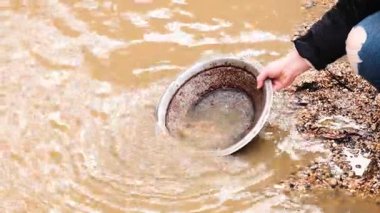 Çamurlu suda altın arayan kişi