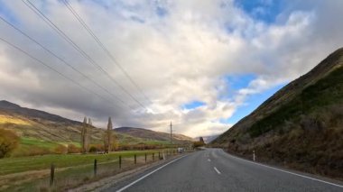 Wanaka 'nın sarmal yollar, yemyeşil tepeler ve dinamik bulut oluşumlarının yer aldığı sakin bir sürüş.