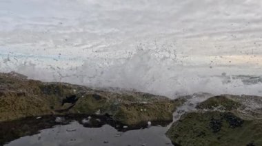Okyanus dalgaları sahilde kayalara çarpıyor.