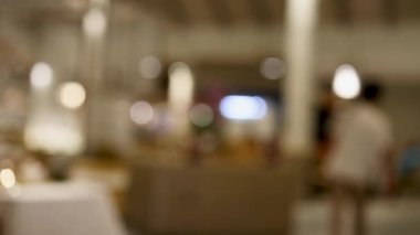 Gece kalabalık bir Tayland restoranının bulanık görüntüsü, ortam aydınlatmasını ve müşterilerin ve personelin hareketlerini yakalıyor.