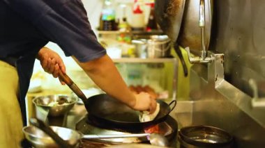 Aşçı ustalıkla mutfakta tavayla yemek pişiriyor.