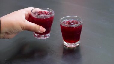 El, masadan bir bardak Roselle suyu alıyor.