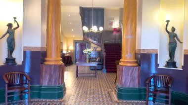 Süslü sütunları, klasik dekorları ve Queenscliff, Victoria 'da sıcak aydınlatma altında büyük bir merdiveni olan klasik bir otel lobisi.