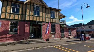 Akaroa 'nın büyüleyici sokaklarında manzaralı bir gezinti, açık mavi gökyüzü altında tarihi mimari ve yerel dükkanlar sergileniyor.