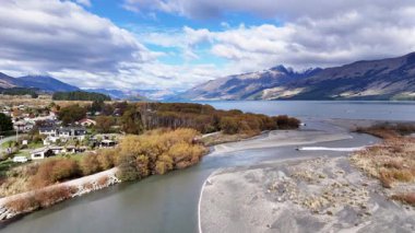 Drone görüntüleri Glenorchy nehrinin, ağaçların ve dağların parlak gökyüzünün altında doğal güzellik ve sükuneti yansıtıyor.