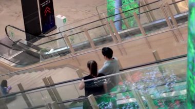 Yürüyen merdivenden birlikte inen iki kişi.